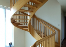 Drewniane, półspiralne schody w przedpokoju